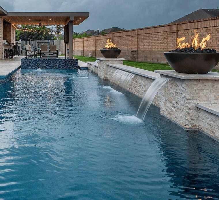 A large swimming pool with a waterfall and a fire pit