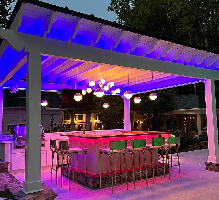 A pergola with a bar and stools underneath it