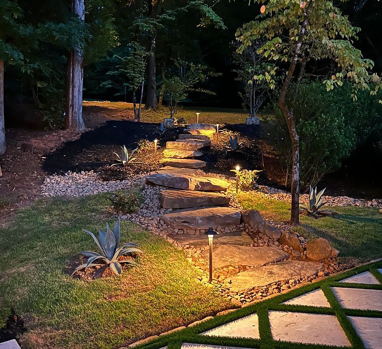 A stone walkway is lit up at night in a backyard.