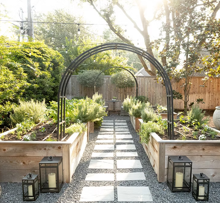 A path leading to a garden with a metal arch and lanterns.