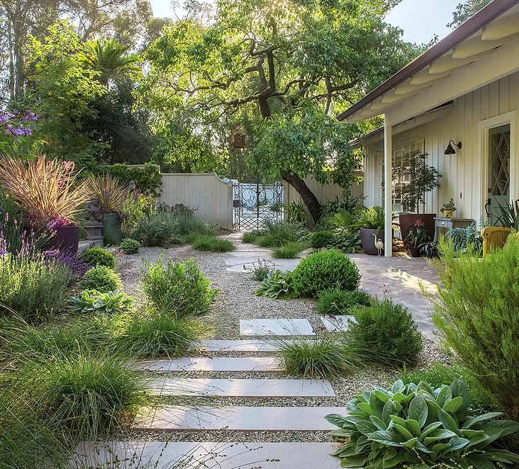 A white house with a lush green garden in front of it
