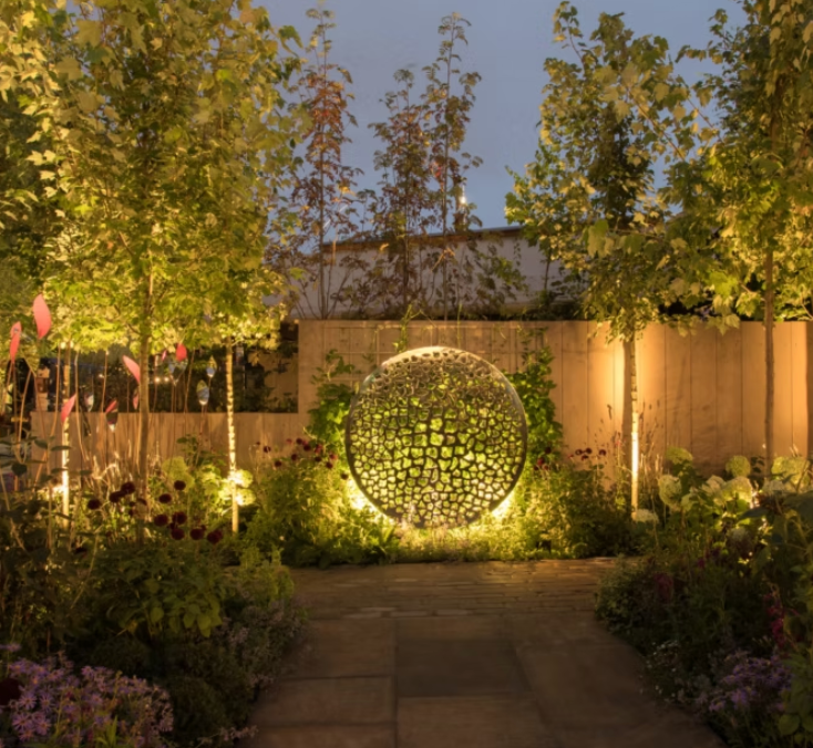 A garden with trees and flowers and a sphere in the middle