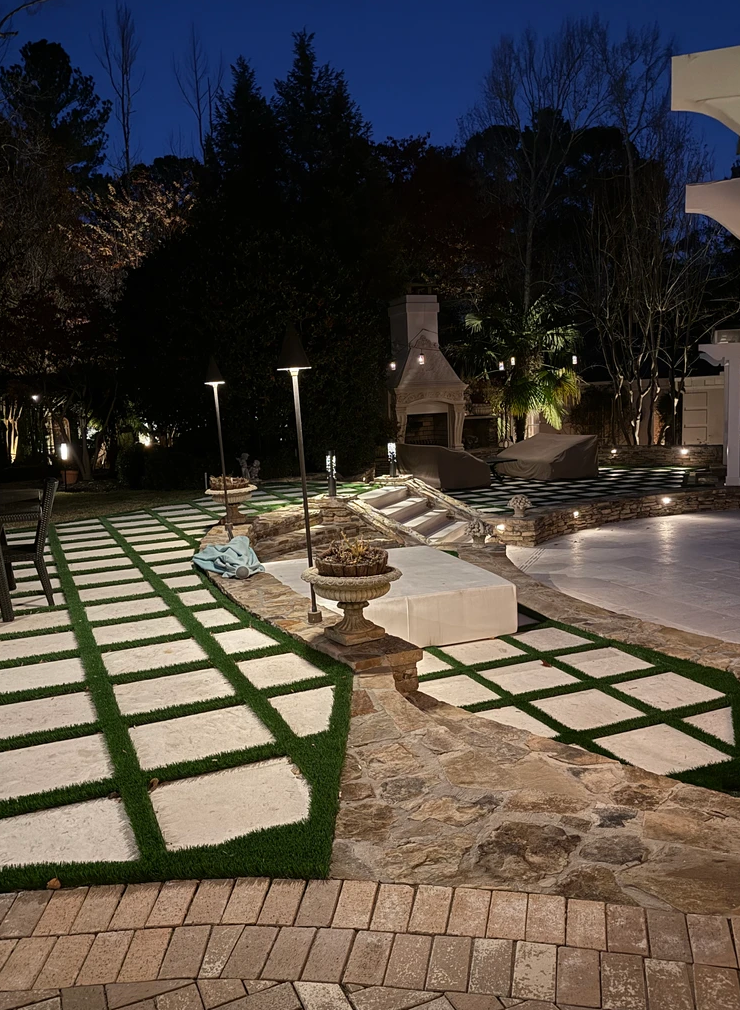 A patio with a fireplace and a swimming pool at night