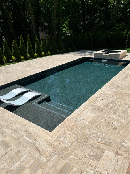 A large swimming pool with two lounge chairs in it