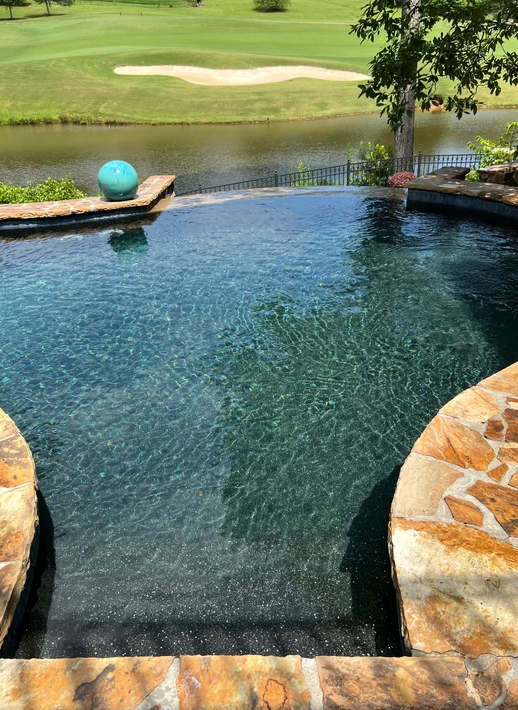 A large swimming pool with a view of a golf course.