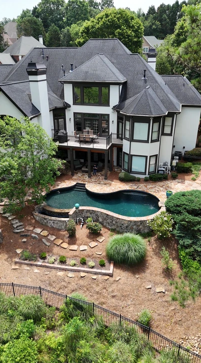 An aerial view of a large house with a large pool in the backyard.