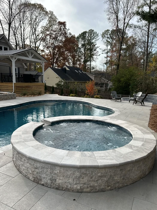 A large swimming pool with a hot tub in the middle of it.
