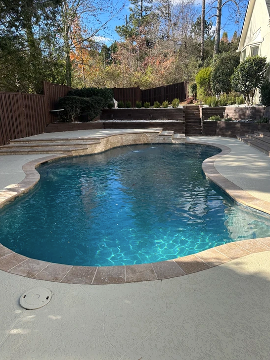 There is a large swimming pool in the backyard of a house.