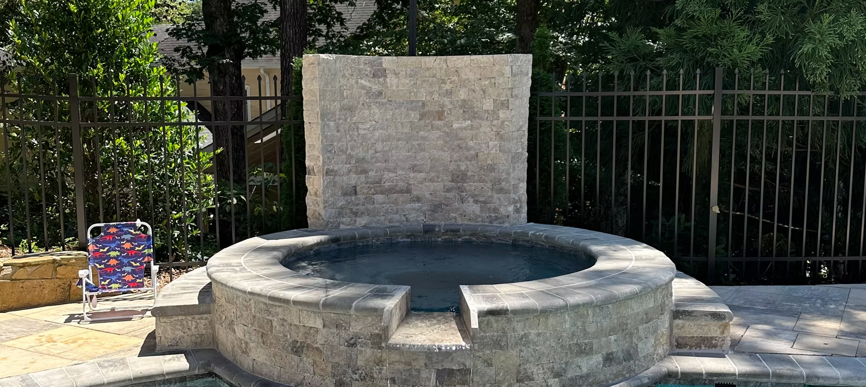 A hot tub is sitting next to a pool in a backyard.