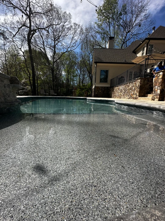 A large swimming pool with a house in the background.