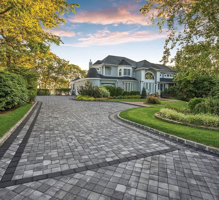 A large house with a brick driveway leading to it.