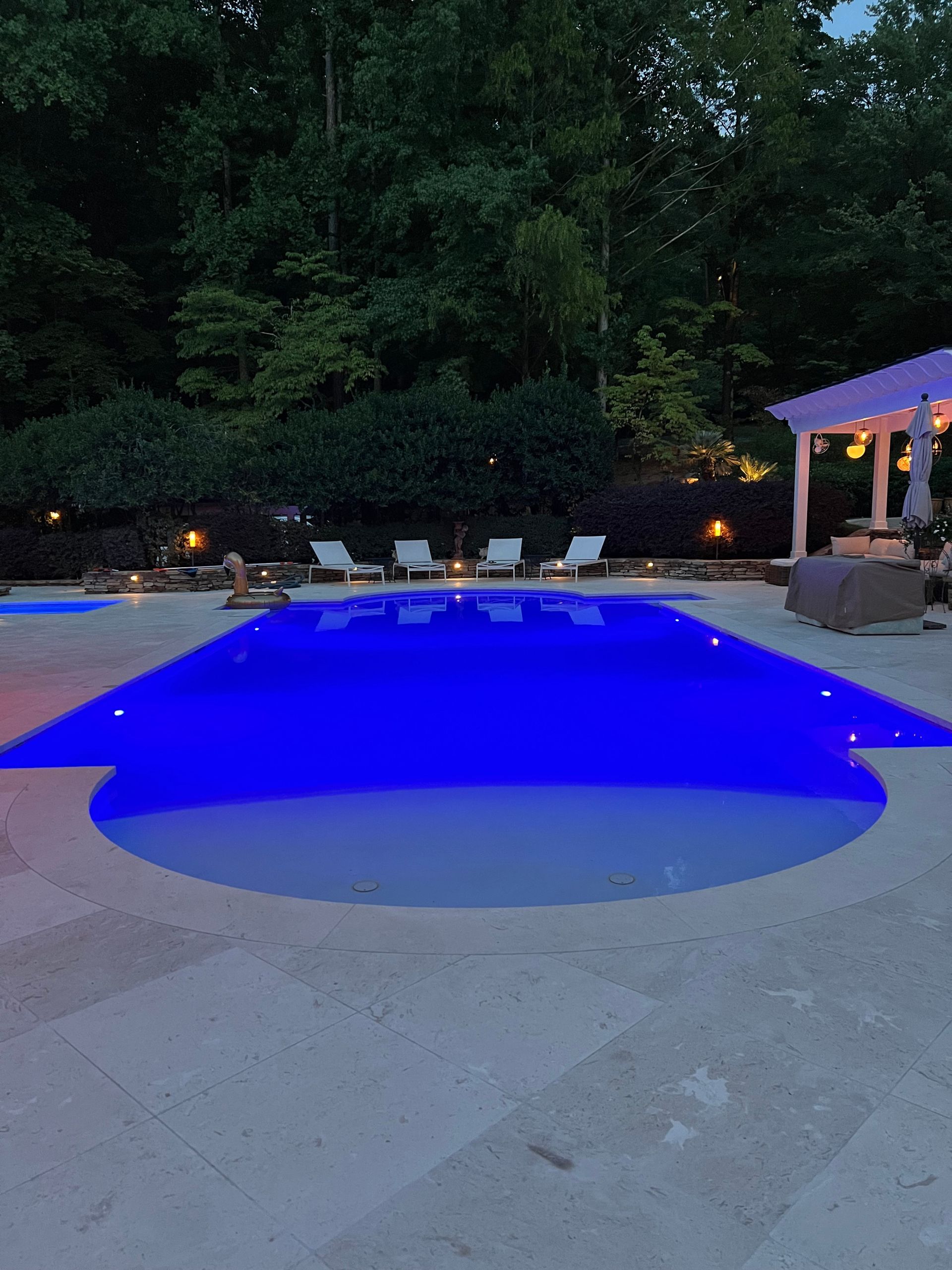 A large swimming pool is lit up with blue lights at night.