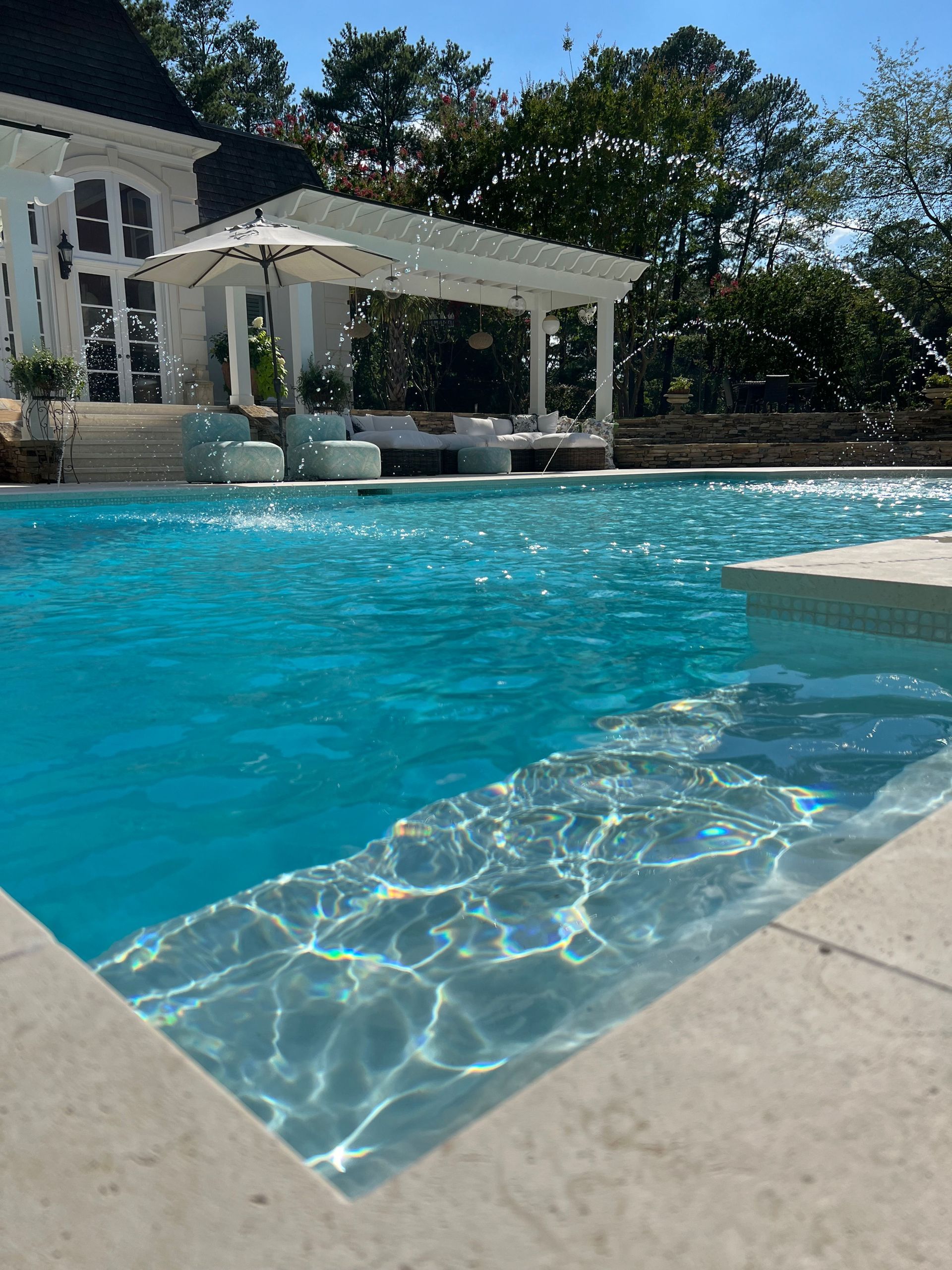 A large swimming pool with a house in the background