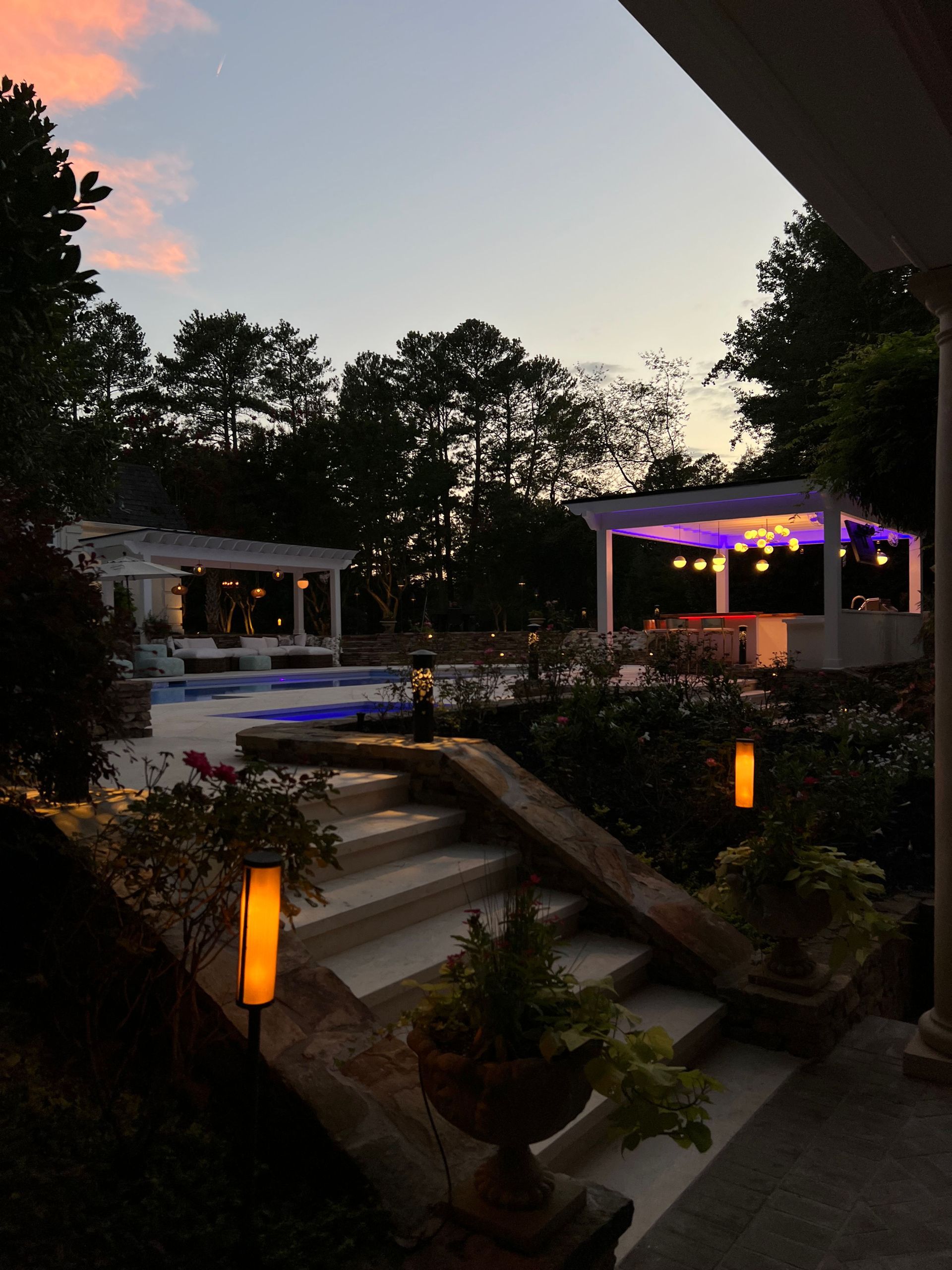 A backyard with a swimming pool and a gazebo at night