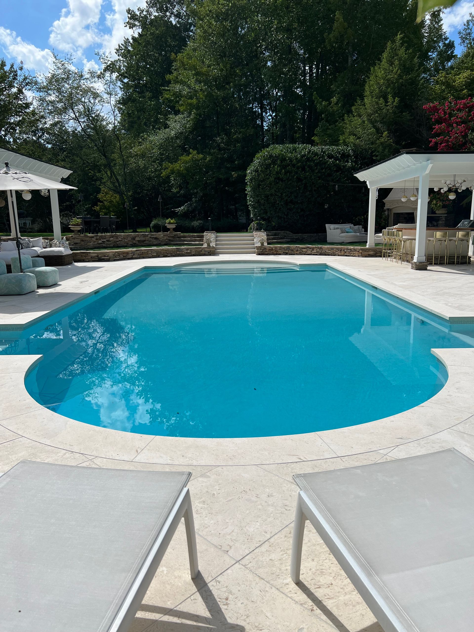A large swimming pool is surrounded by chairs and umbrellas.