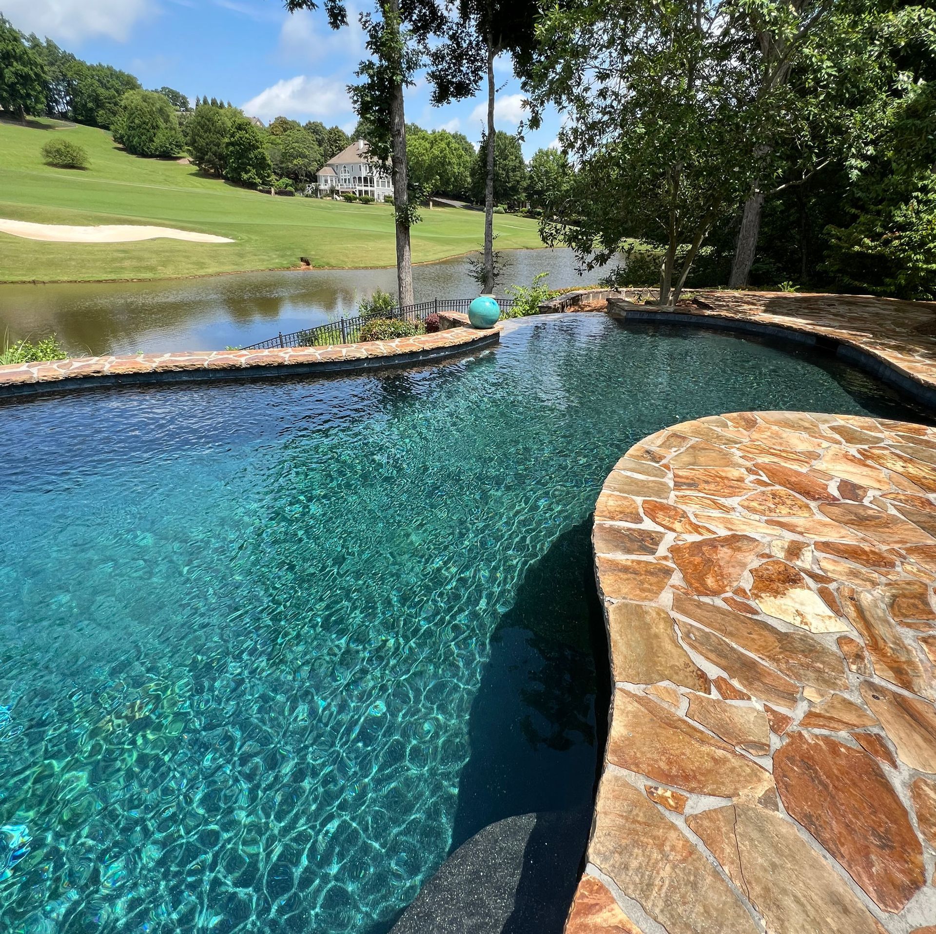 A large swimming pool surrounded by trees and a golf course