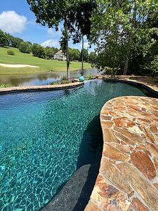 A large swimming pool surrounded by trees and a golf course.