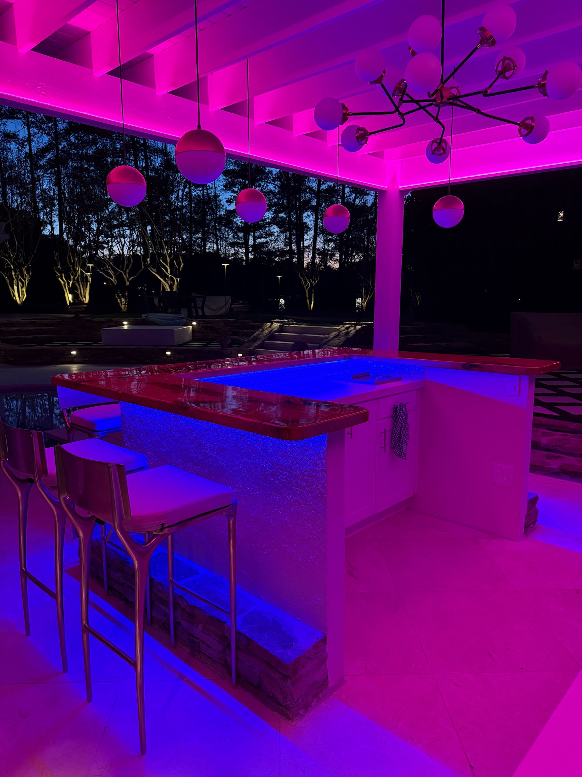 A bar with purple and blue lights is lit up at night.