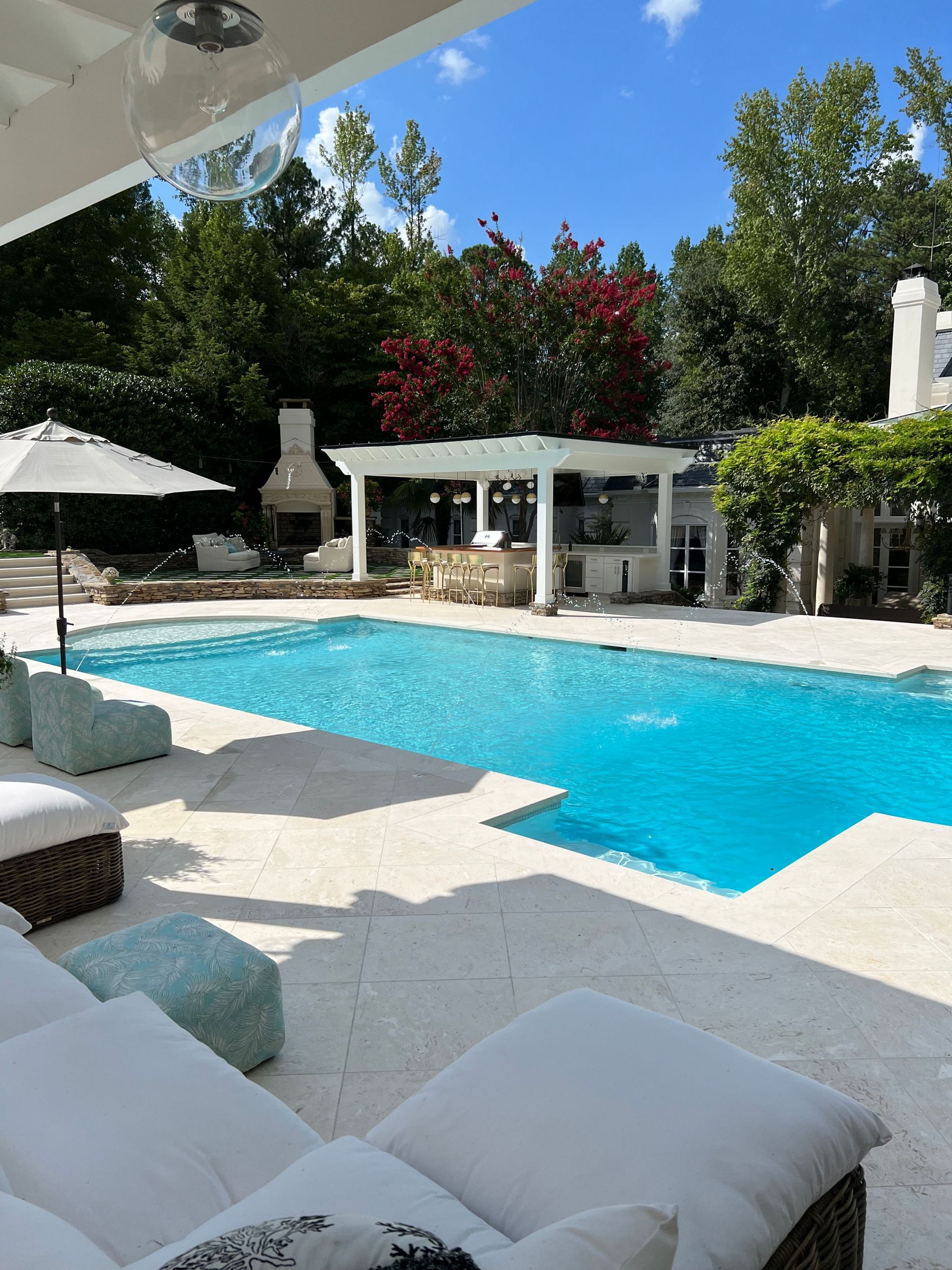A large swimming pool surrounded by chairs and umbrellas