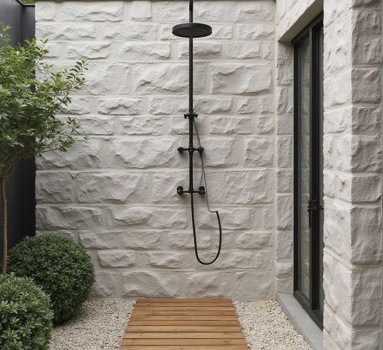 An outdoor shower with a brick wall and a wooden walkway