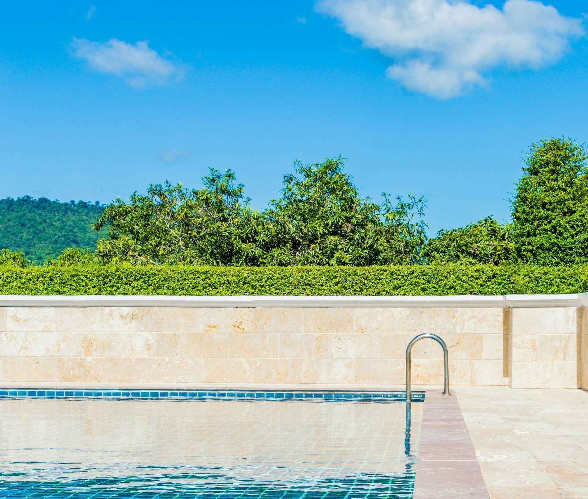 A swimming pool with a ladder leading to it on a sunny day.