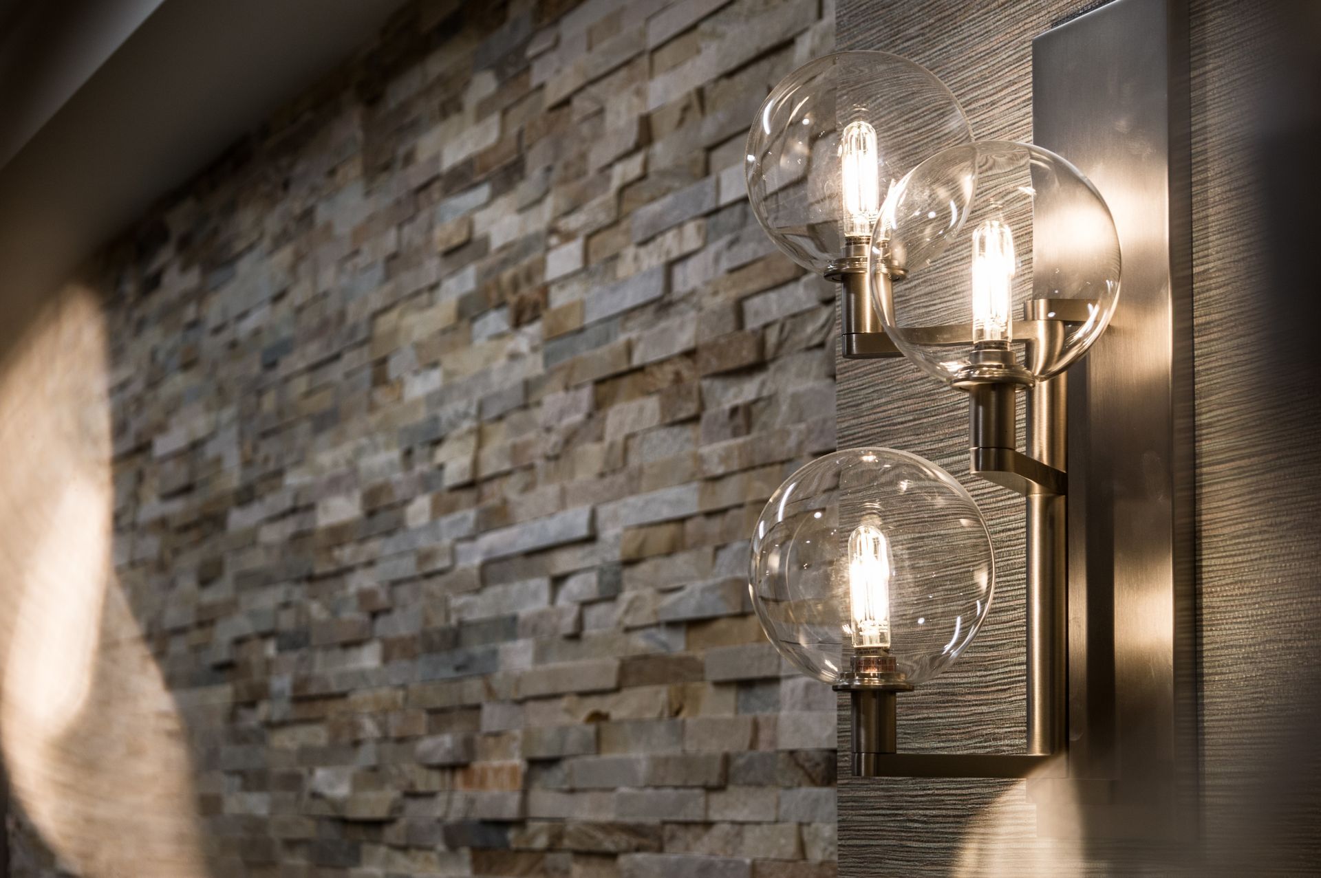A wall light is hanging on a stone wall.