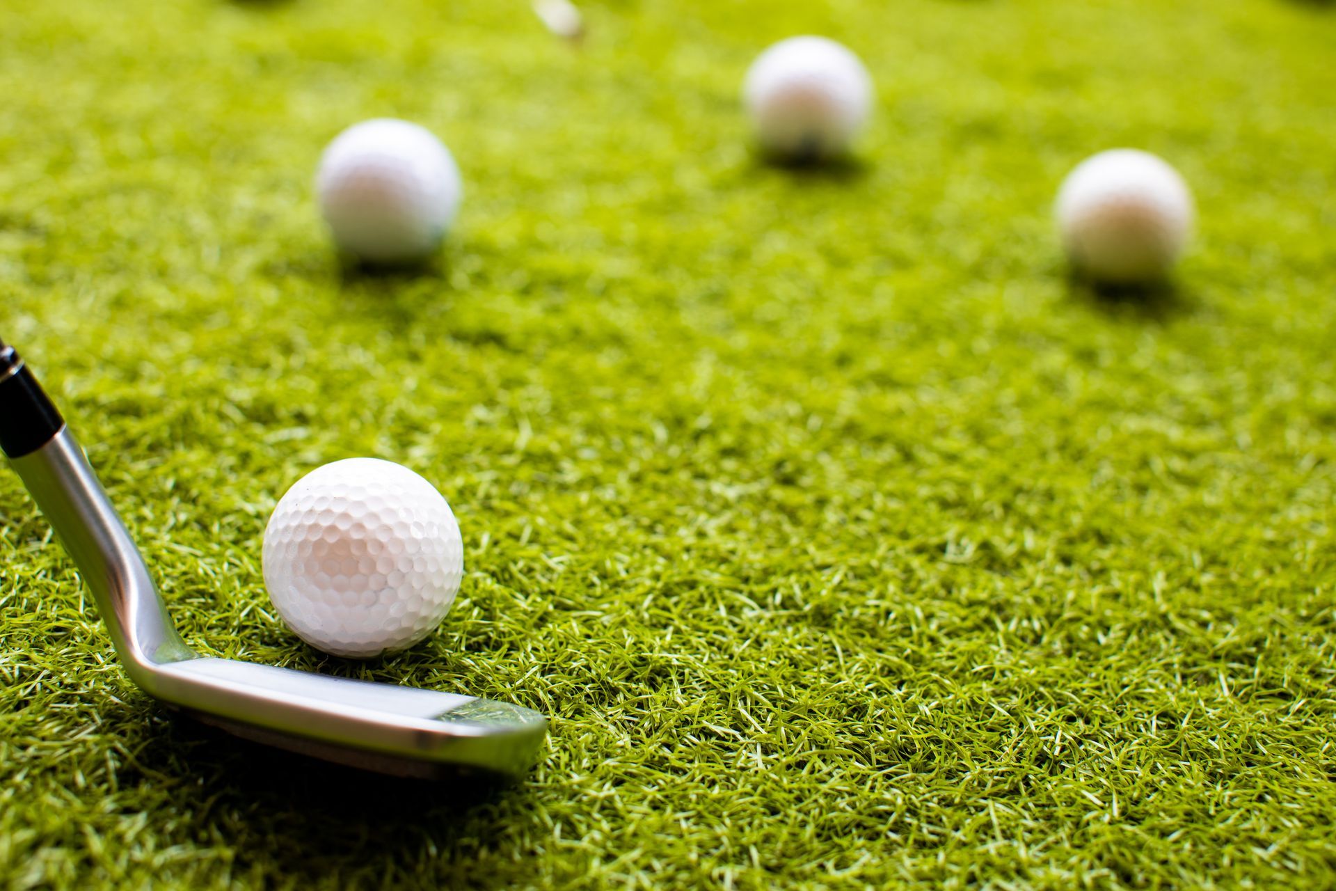 A golf club is sitting on top of a golf ball on a green field.