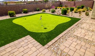 A backyard with a putting green and a brick walkway.