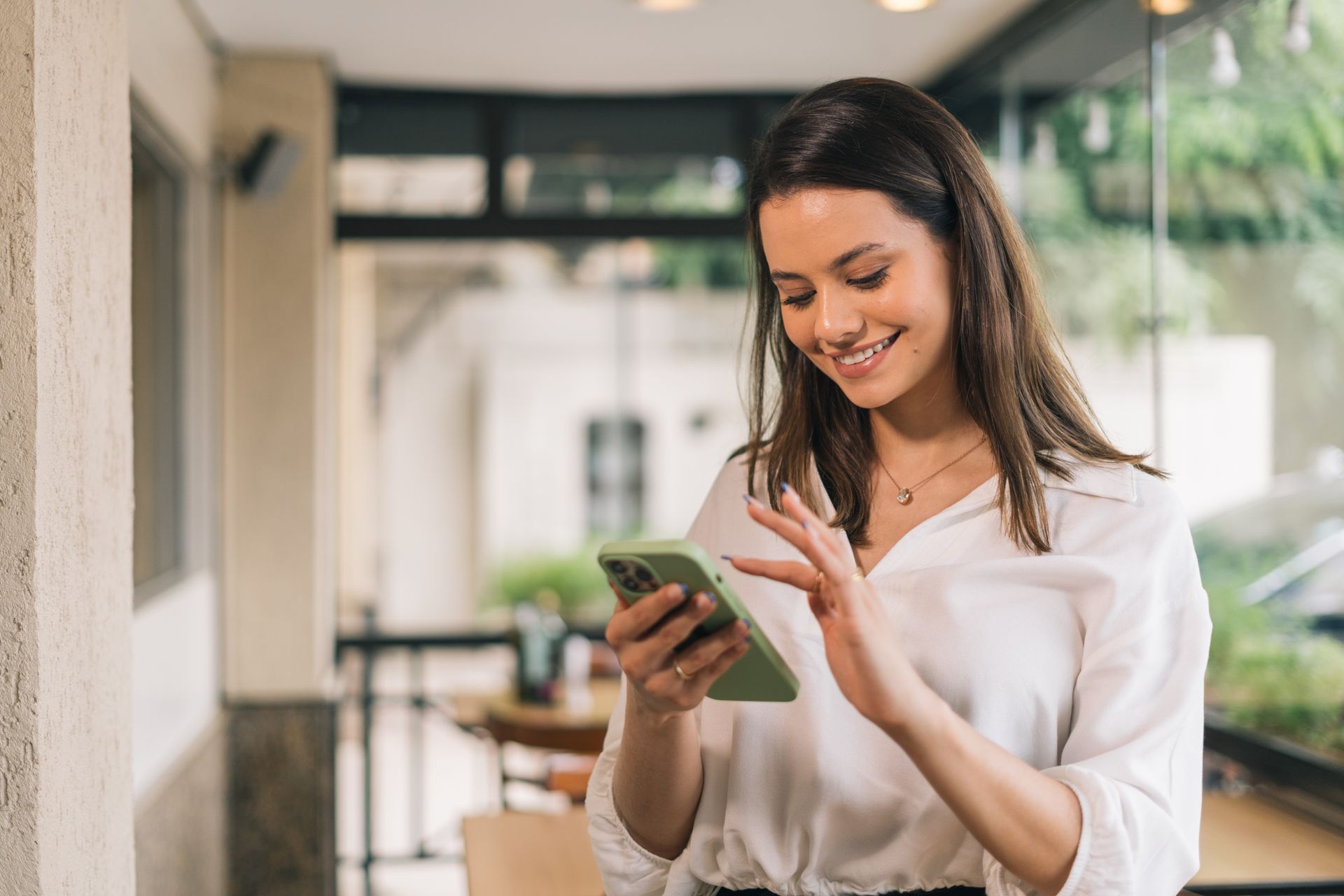 A woman is smiling while looking at her cell phone.