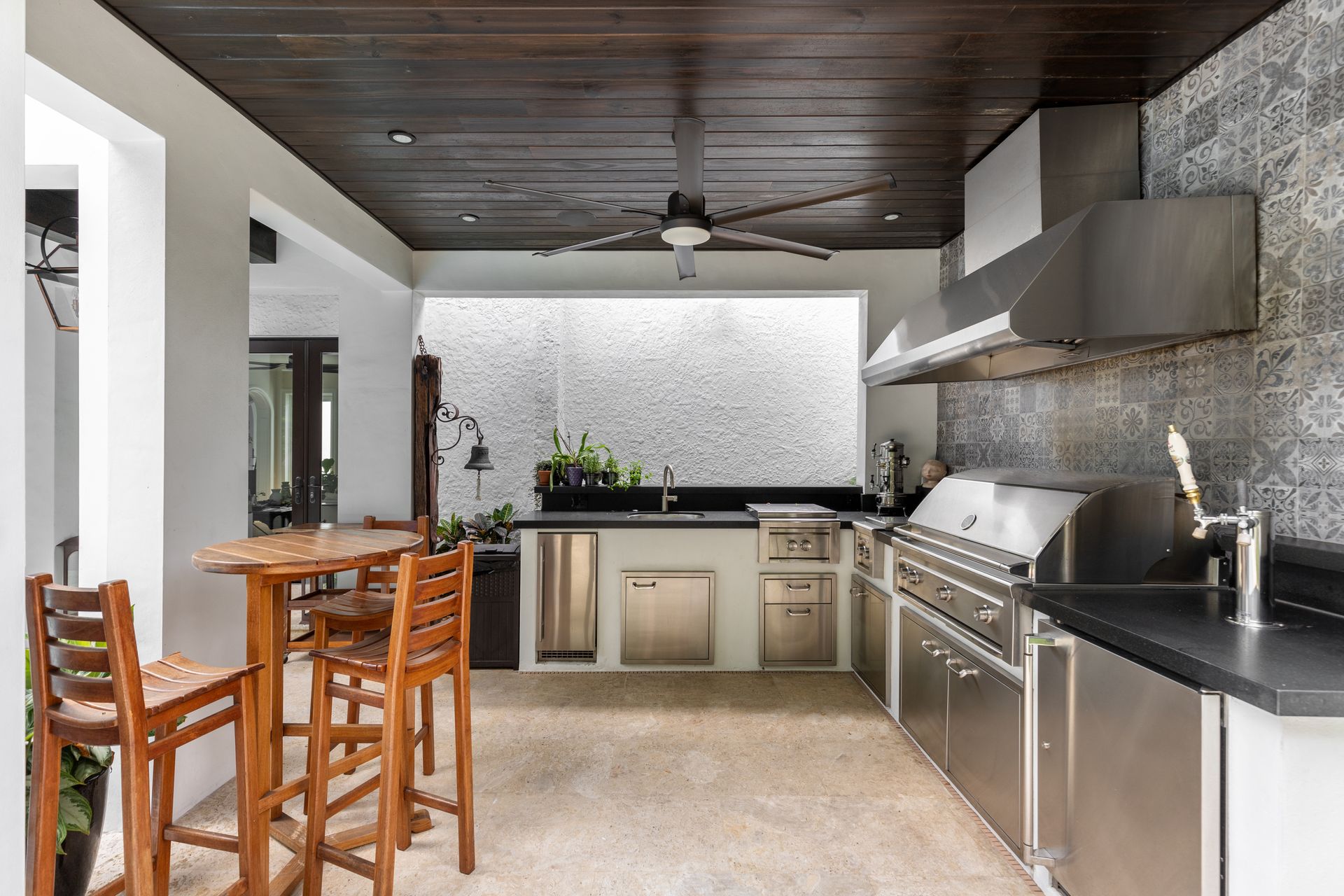 A kitchen with stainless steel appliances and wooden tables and chairs.