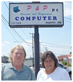 two people standing in front of a p & p pc computer sign