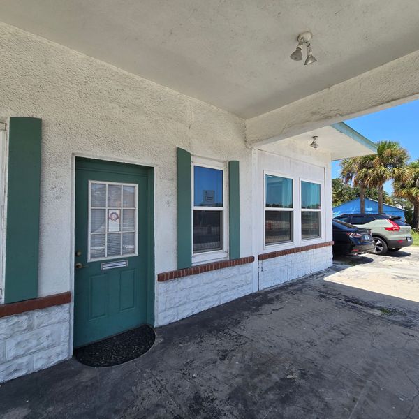 A white building with green shutters and a green door