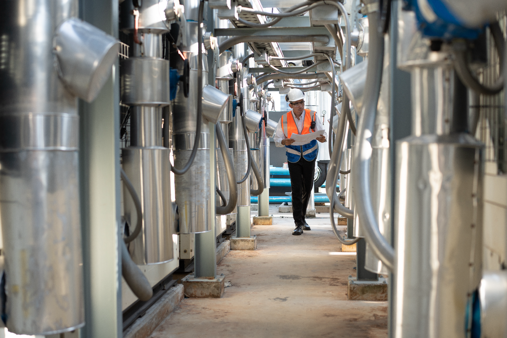 A man is walking down a hallway in a factory.