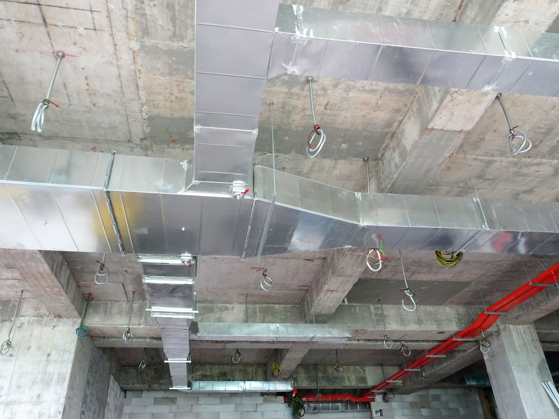 A ceiling with a lot of metal pipes hanging from it.