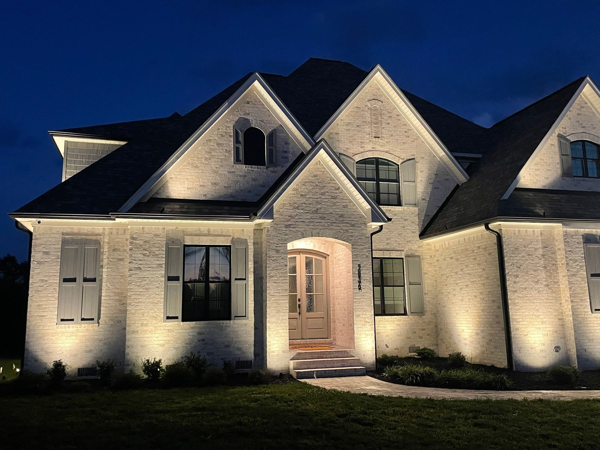 A large white brick house is lit up at night