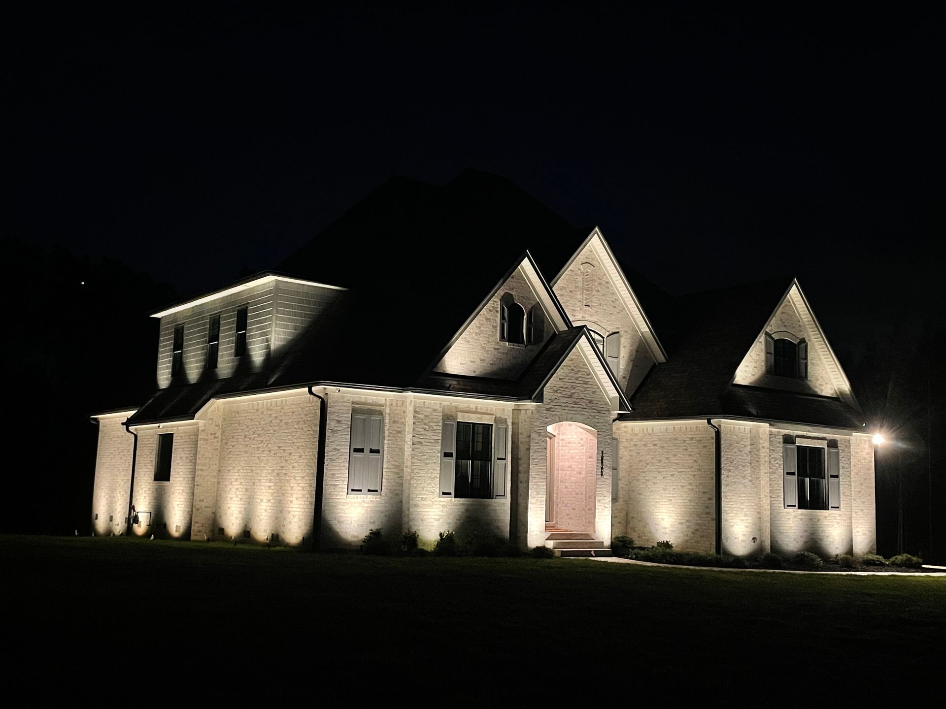 A large white house is lit up at night.