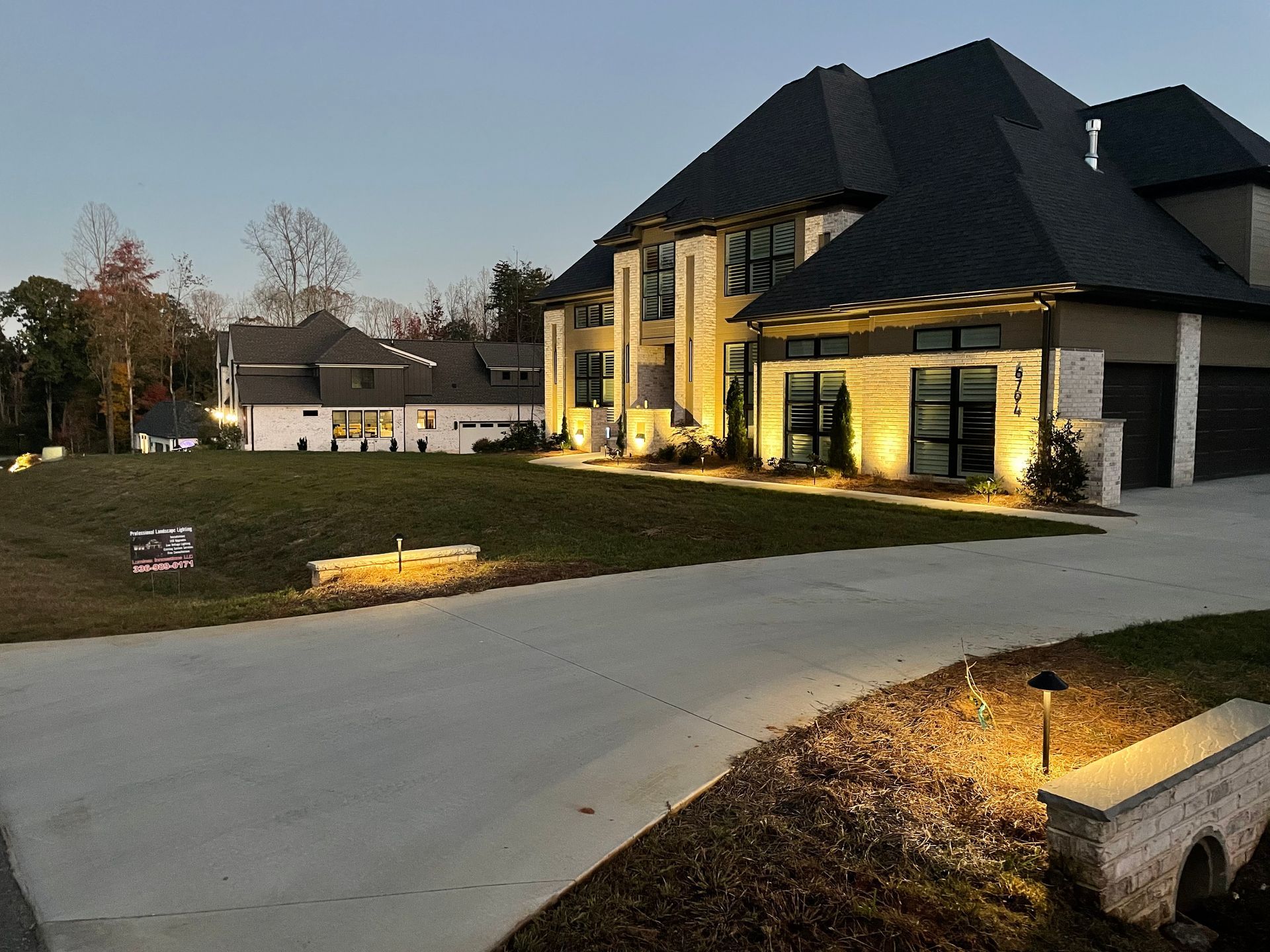A large house with a large driveway is lit up at night.