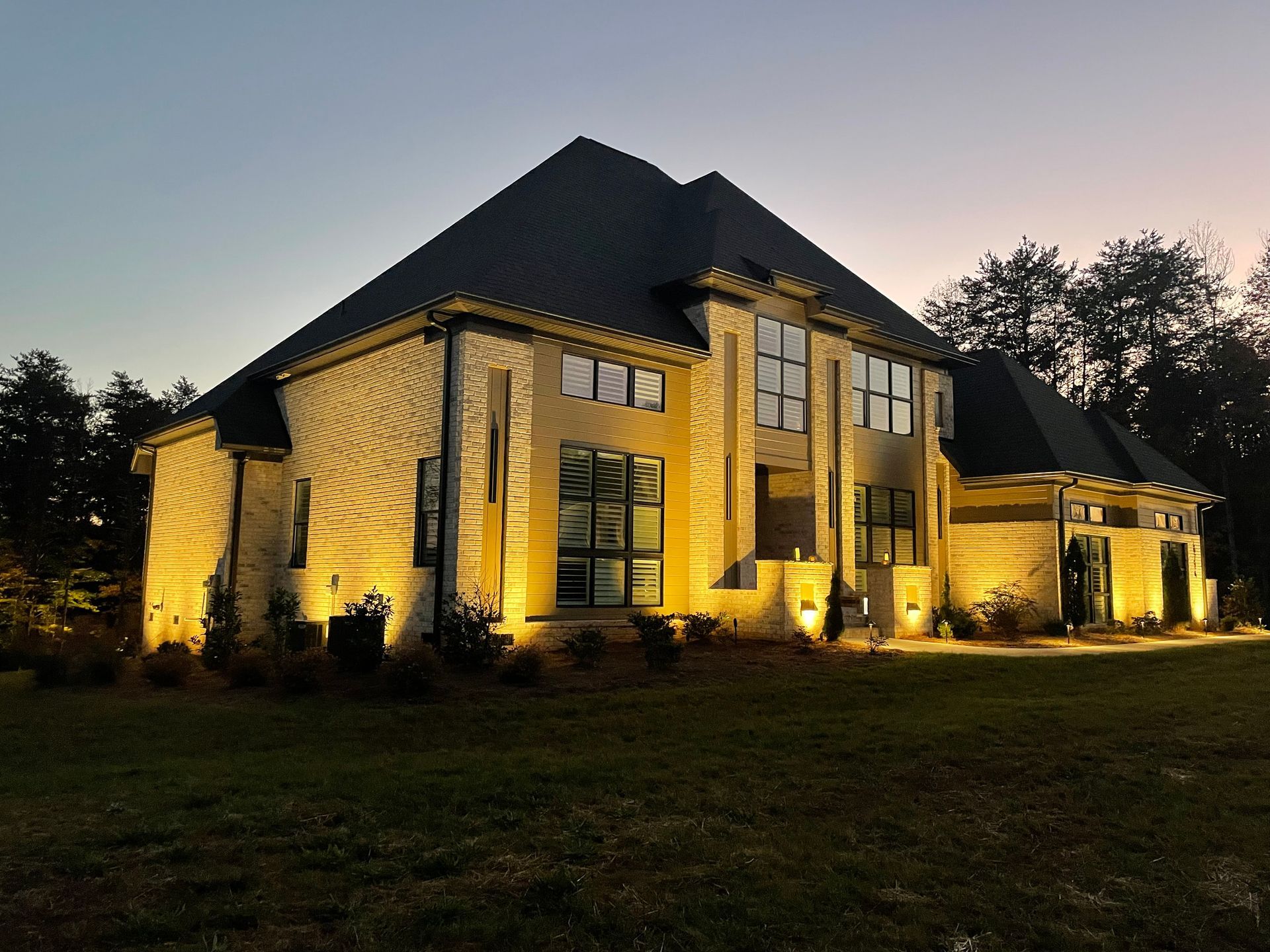 lakeside home is lit with architectural lighting at night