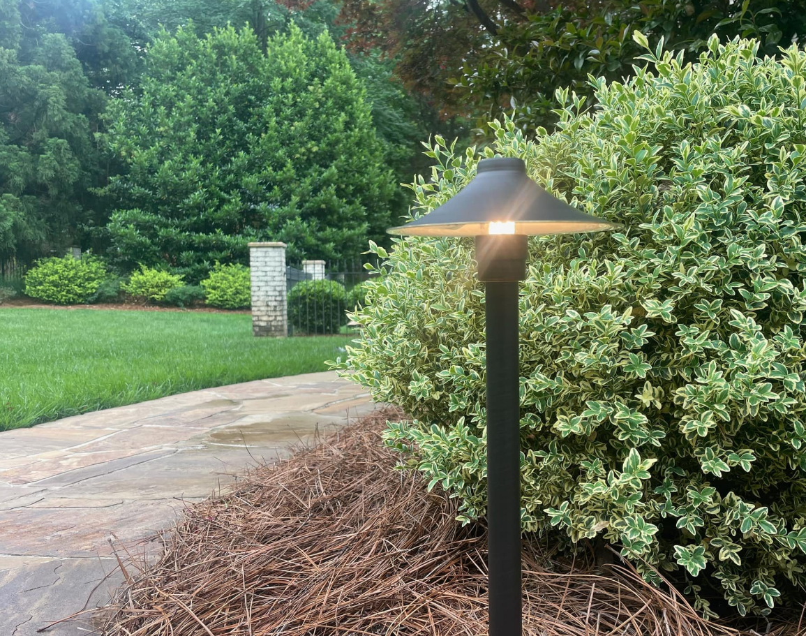 an outdoor light post lighting a pathway in the evening.
