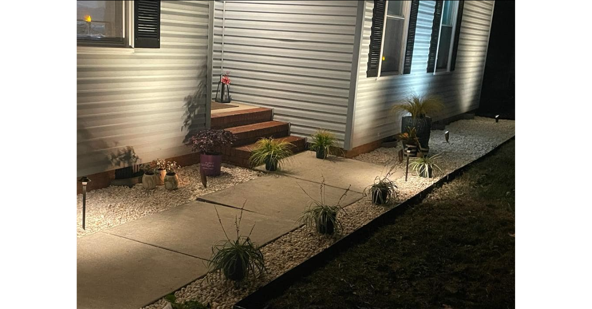 The front walkway of a house is lit at night with professional outdoor lights.
