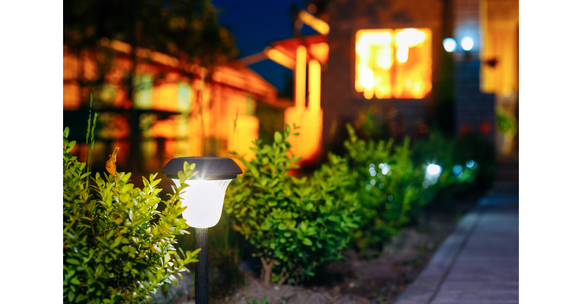 A pathway light is lit up in front of a house at night.