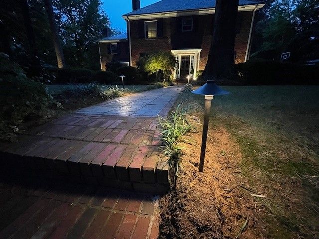 A wooden deck with stairs leading up to a house, list with small pathway lanterns