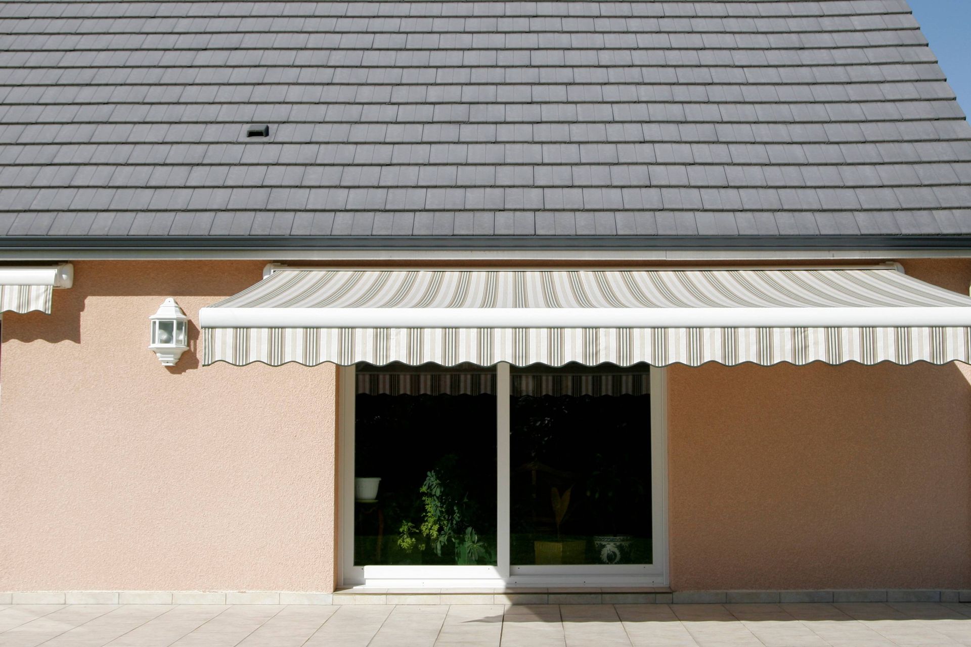 A retractable awning, opened and covering a home's sliding glass door and the patio near Coeur d'Alene, ID