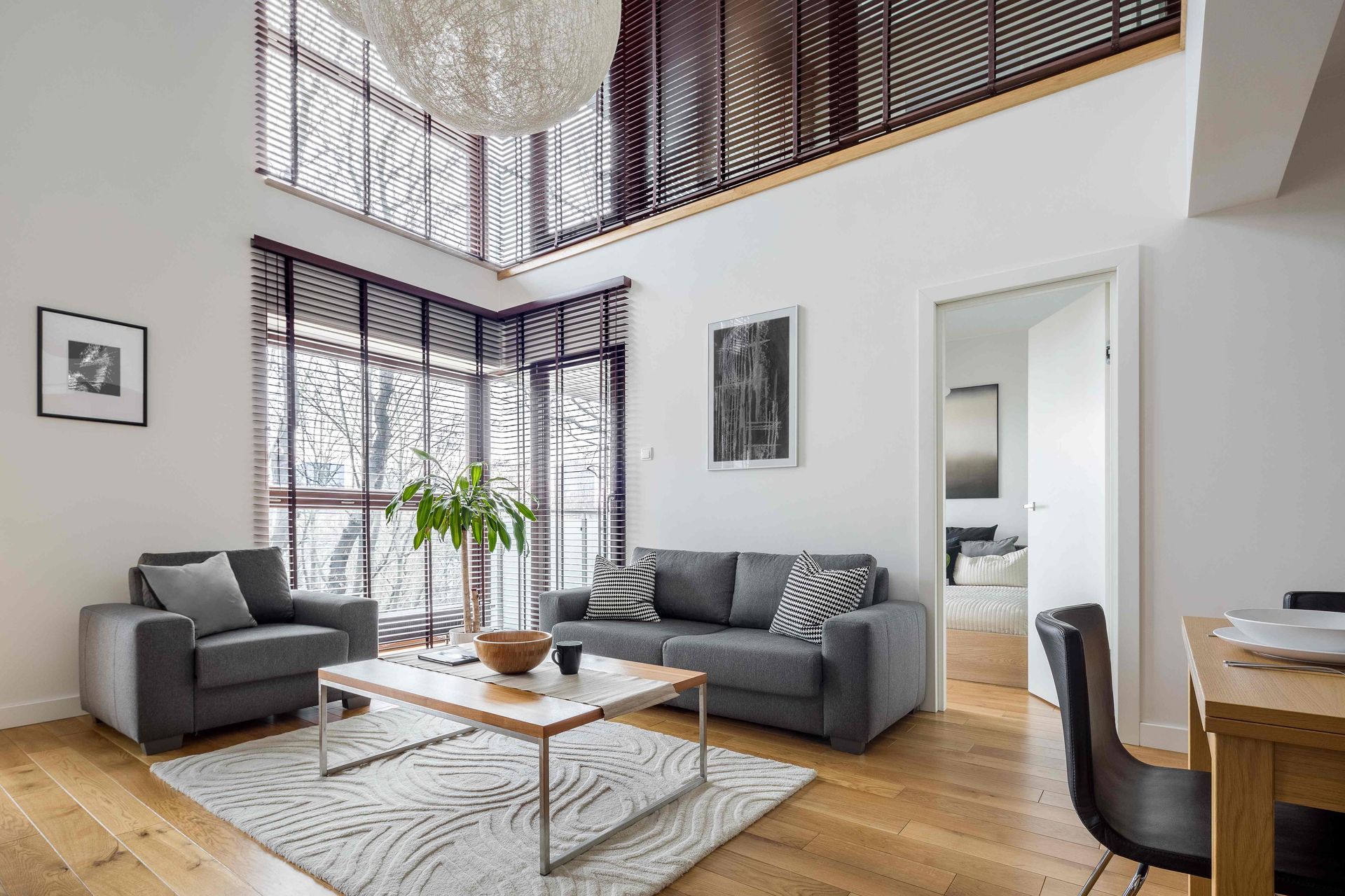 A contemporary living room with an open floor plan and stylish yet functional window blinds near Coe