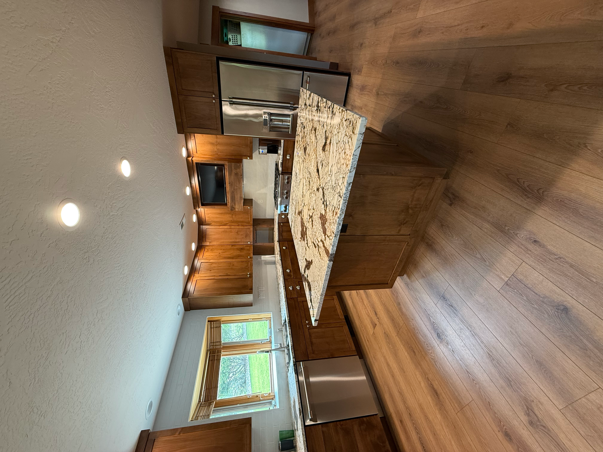 Kitchen with granite island and stainless steel appliances; hardwood floors.