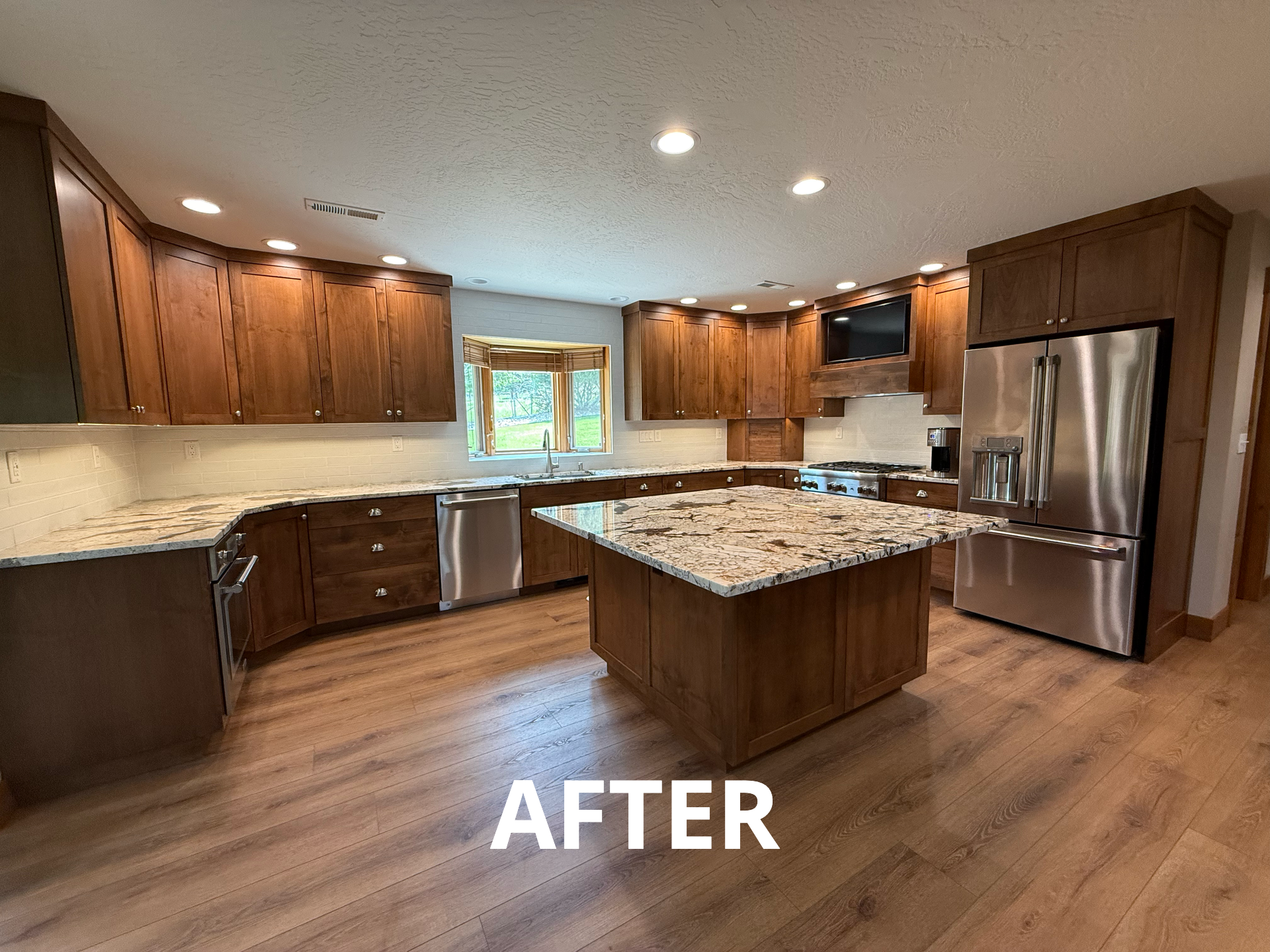 Newly renovated kitchen with brown cabinets, granite countertops, stainless steel appliances, and wooden floors.