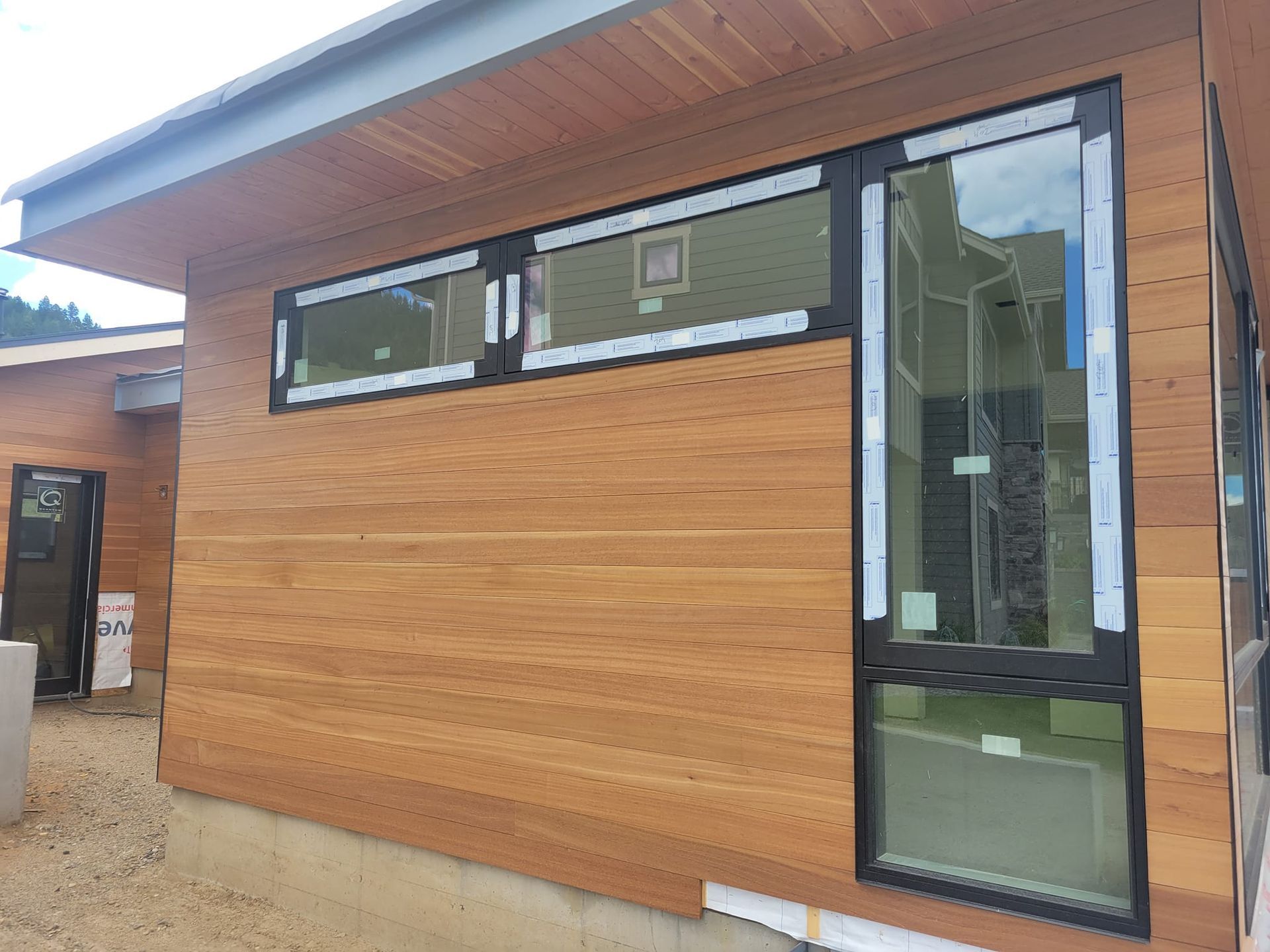 Exterior of a building under construction, with cedar siding and black-framed windows.
