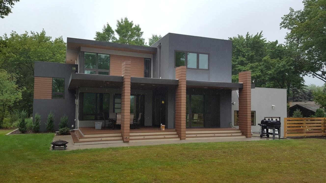 A large house with a lot of windows is sitting on top of a lush green field.