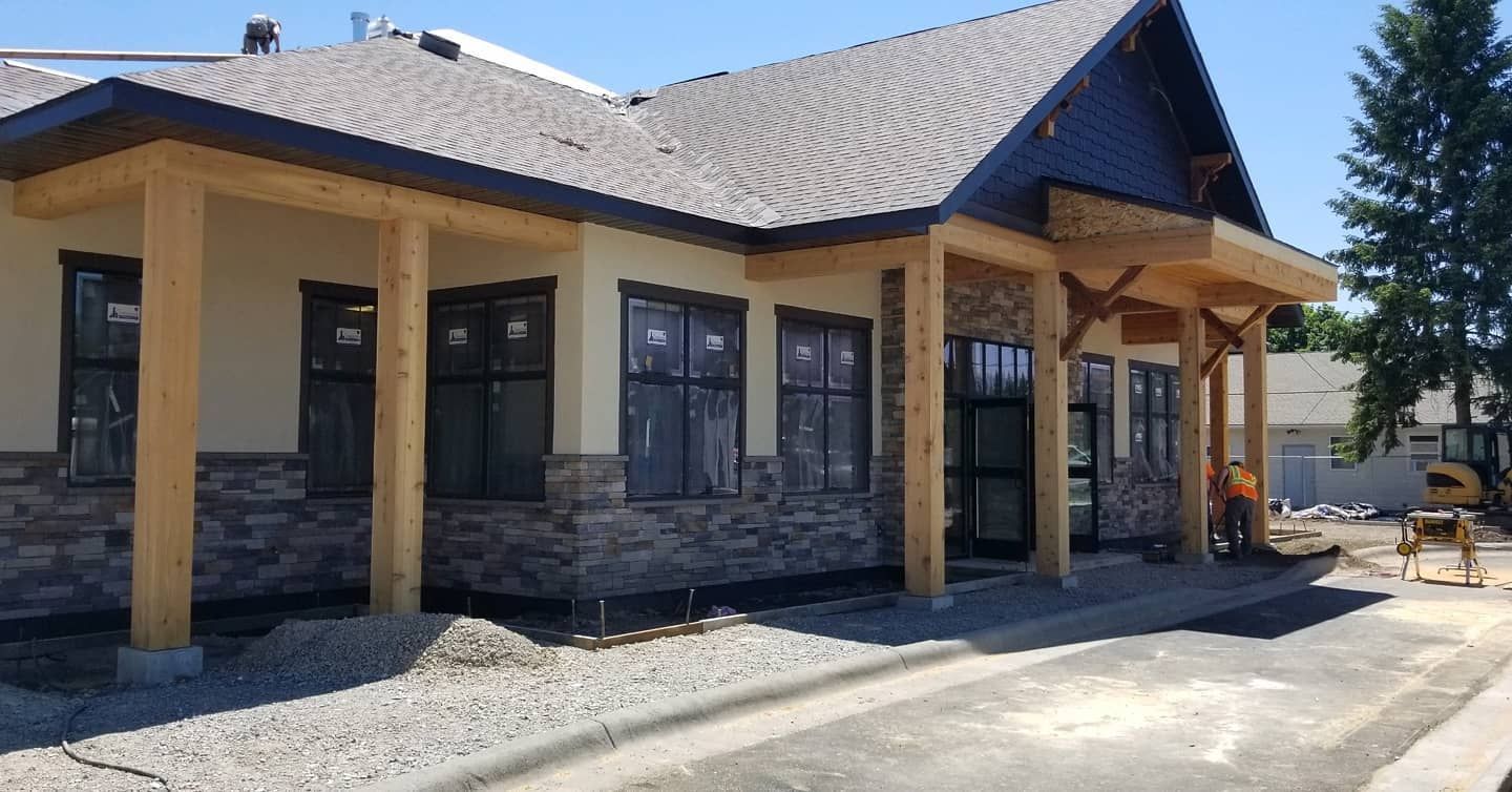 A large house with a porch and a lot of windows is being built.