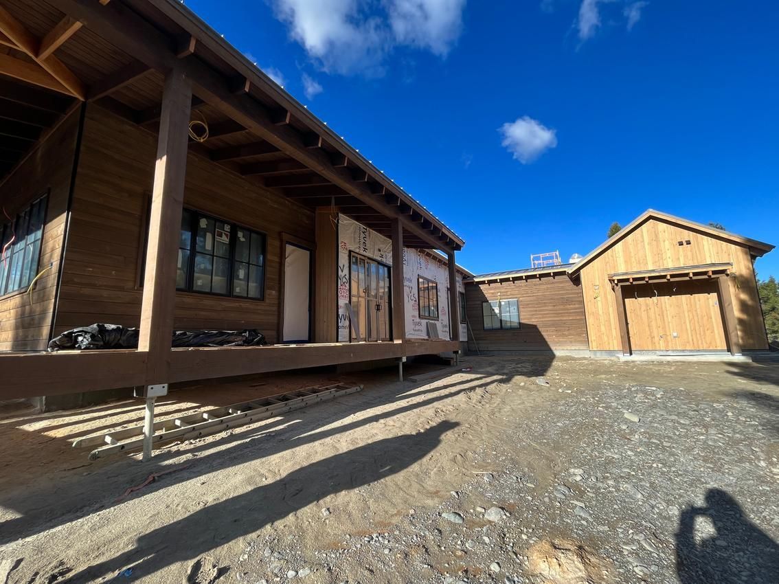 Wooden cabin with porch and detached garage under a bright blue sky.